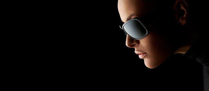 Person wearing dark sunglasses against a black background